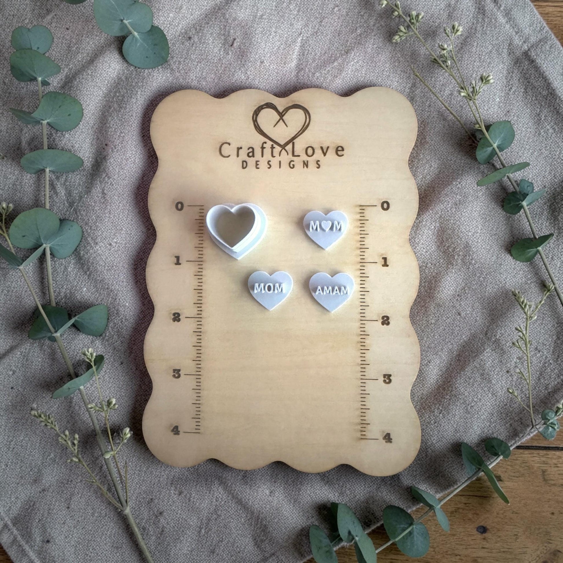 heart clay cutter and word heart charms displayed on ruler board