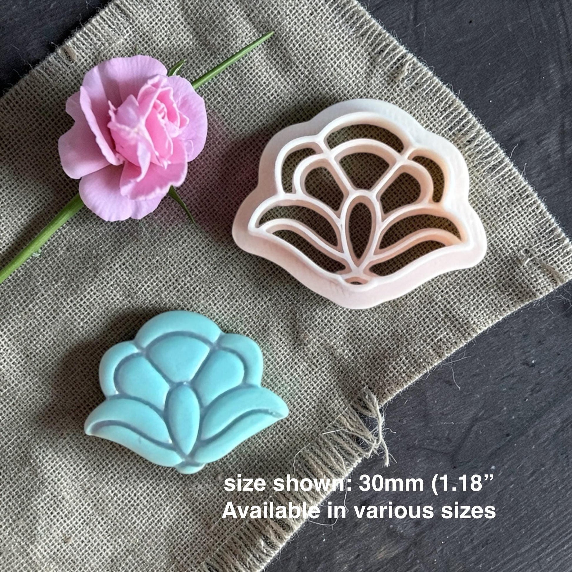 Polymer clay cutter and finished turquoise clay flower displayed on burlap fabric with a pink flower, showing the cutter and final design with text noting size shown 30mm.