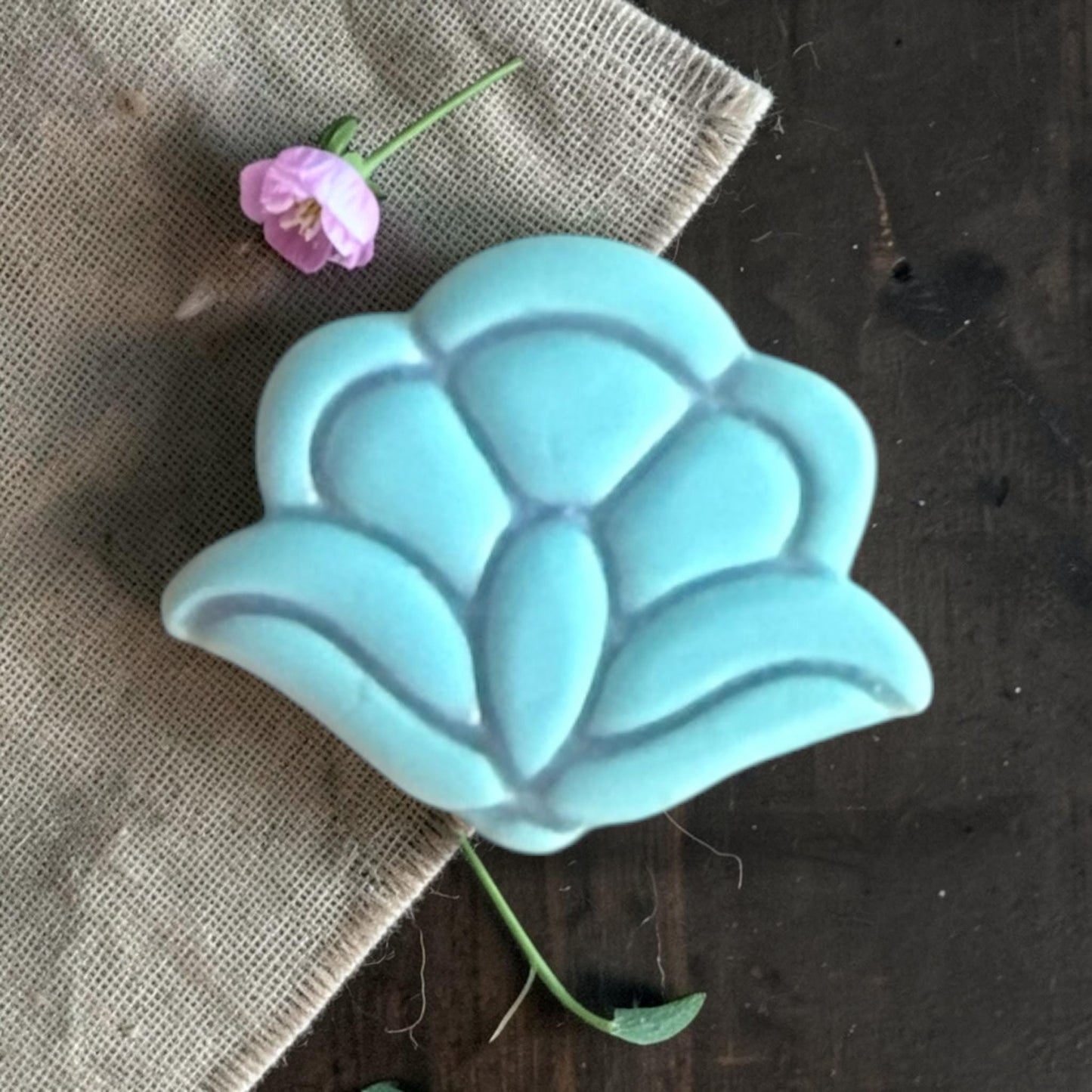 Close-up of a turquoise clay floral shape showing the raised petal details and layered flower design.