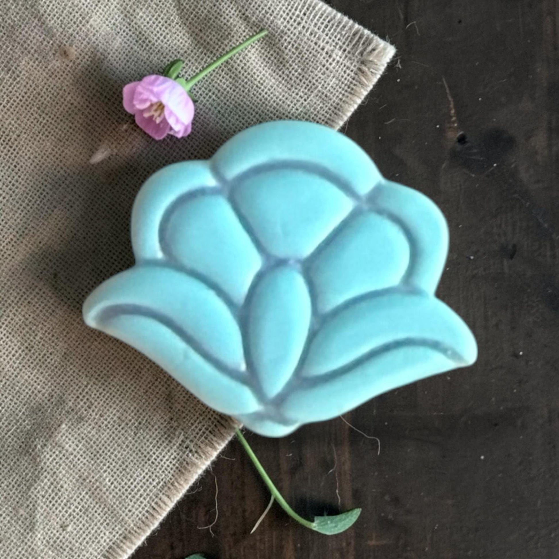 Close-up of a turquoise clay floral shape showing the raised petal details and layered flower design.