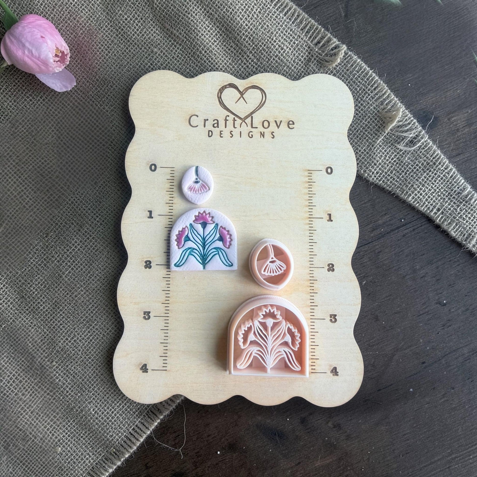 clay imprints and cutters arranged on wooden sizing board with flower