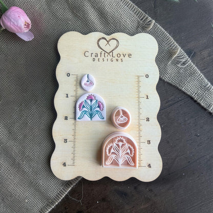 clay imprints and cutters arranged on wooden sizing board with flower
