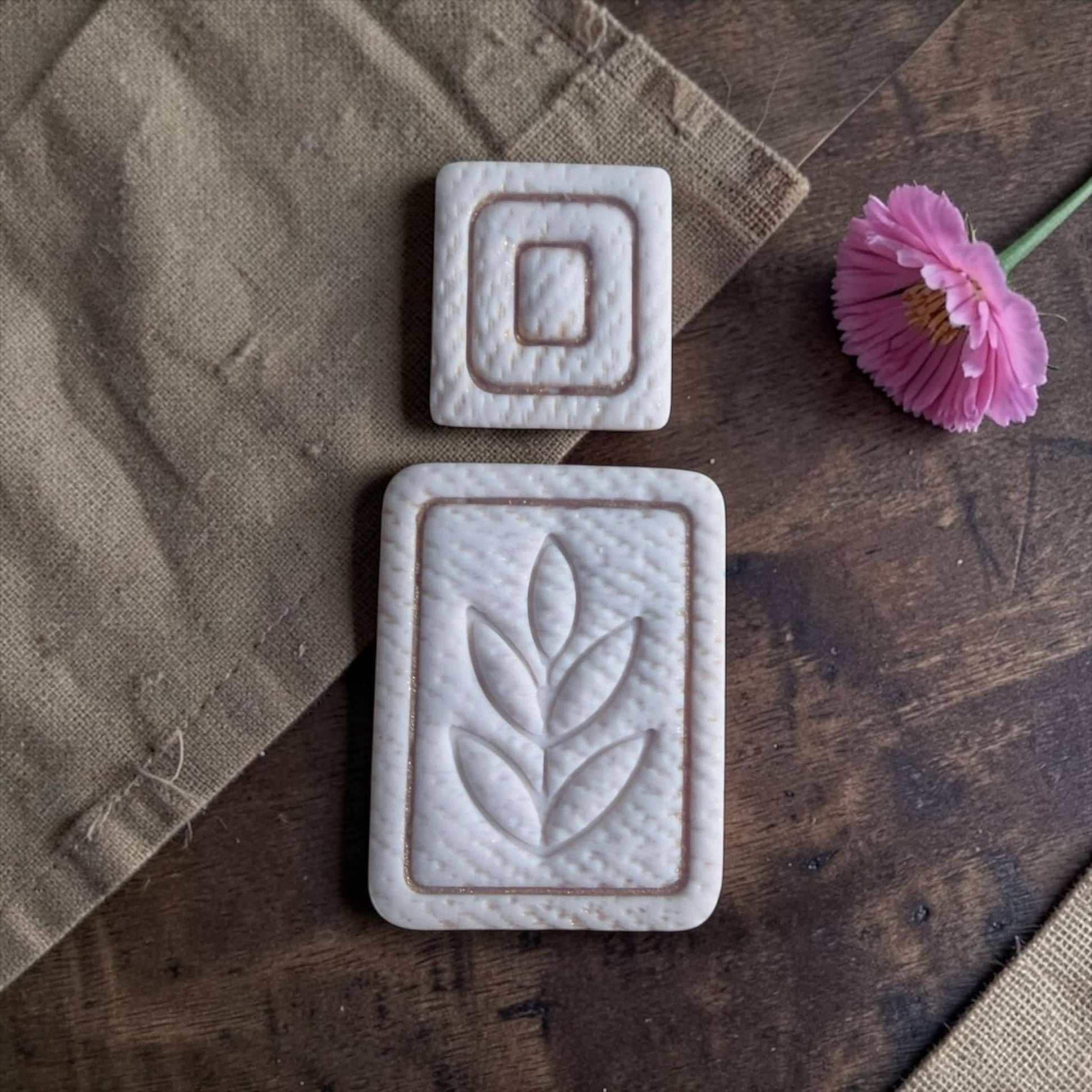 white clay imprints of square topper and leaf rectangle on dark wood