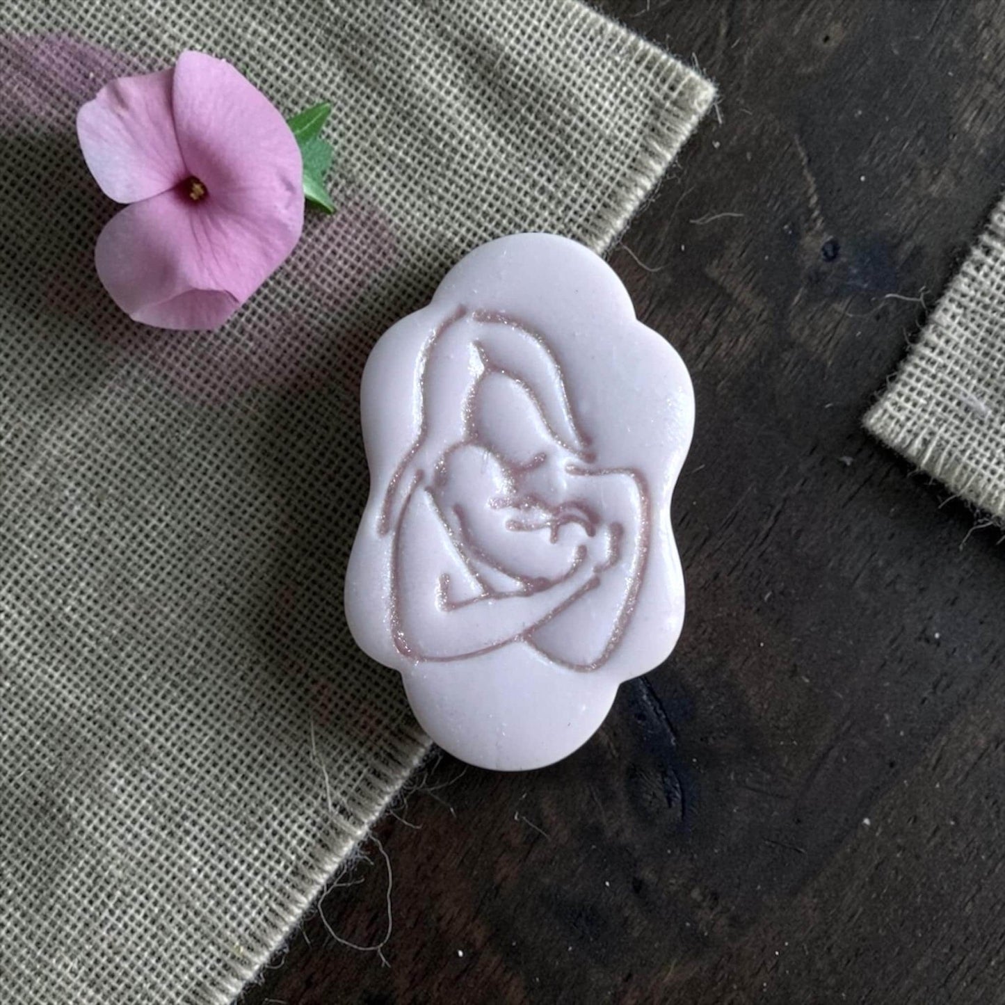 Finished clay imprint of mother holding baby silhouette on burlap with pink flower