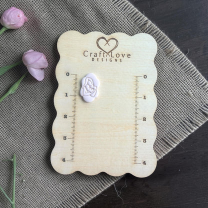 Finished mother and baby clay imprint on Craft Love Designs measuring board with two pink buds