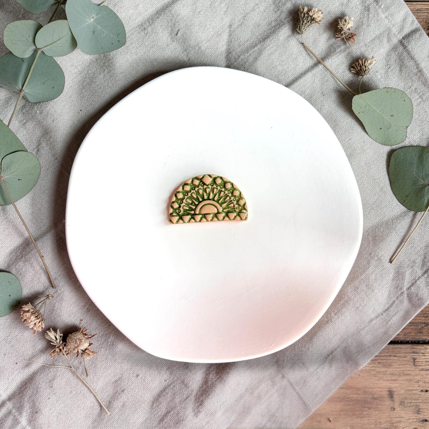Finished clay arch piece in green showing detailed geometric fan and sunburst texture on a white plate.