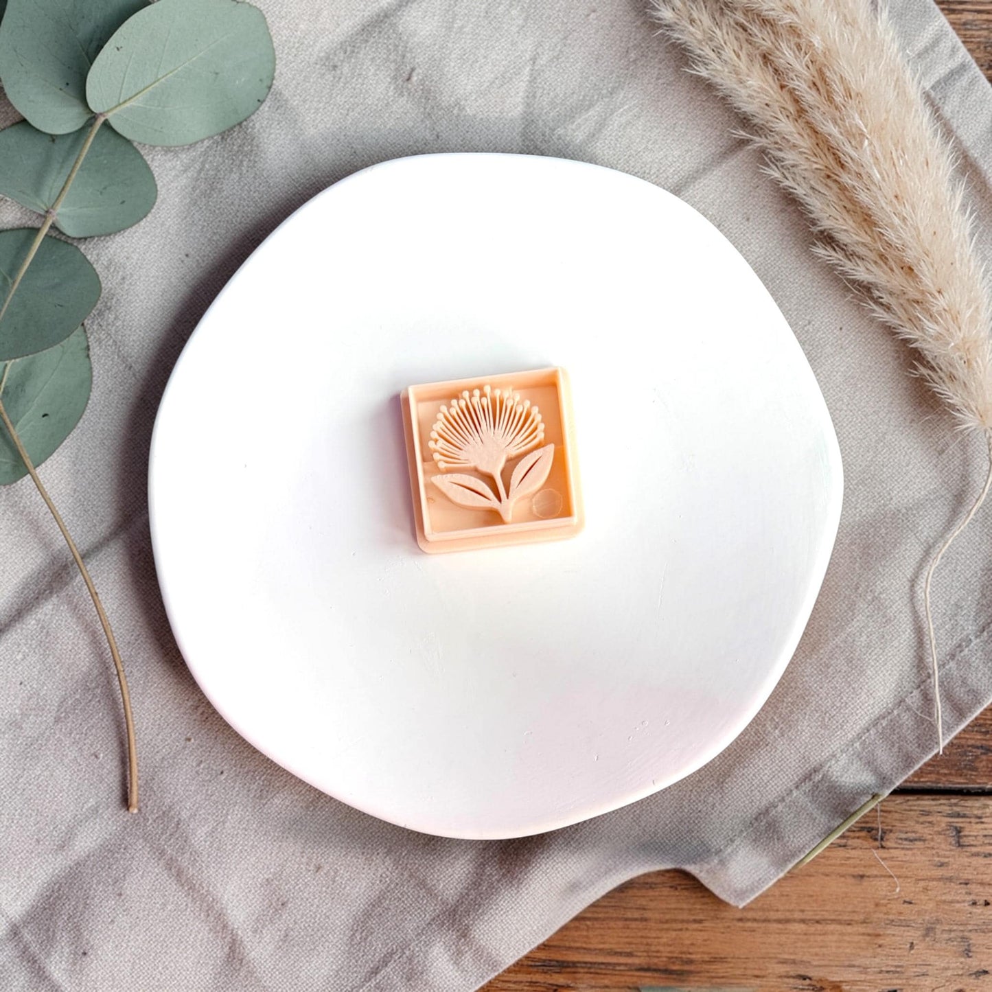 Polymer clay cutter and finished square clay piece side by side with text showing size 32mm on a white plate.