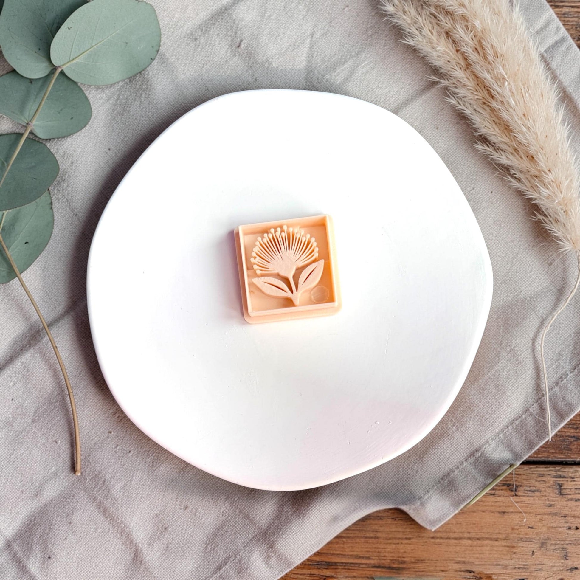 Polymer clay cutter and finished square clay piece side by side with text showing size 32mm on a white plate.