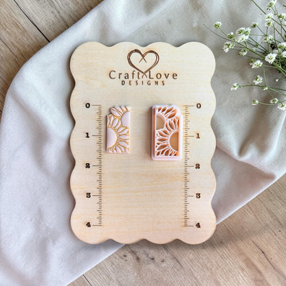 Two rectangular pieces on a wooden measuring board, one sunflower polymer clay cutter and one finished clay piece with gold detailing.
