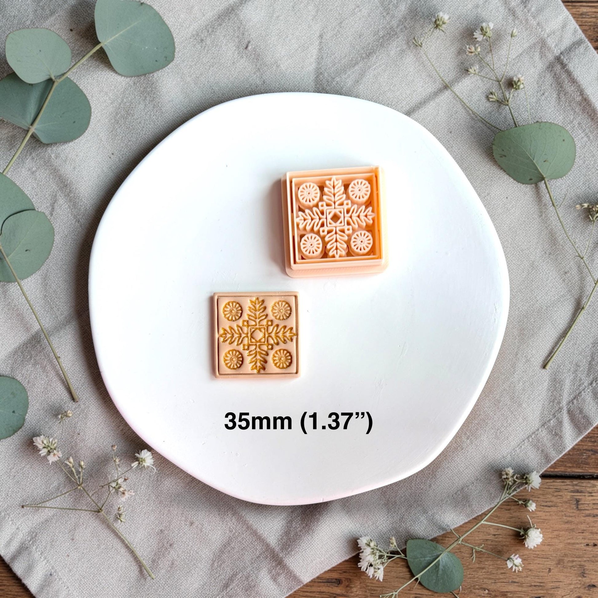 Polymer clay cutter and finished square clay piece side by side with text showing size 35mm on a white plate.