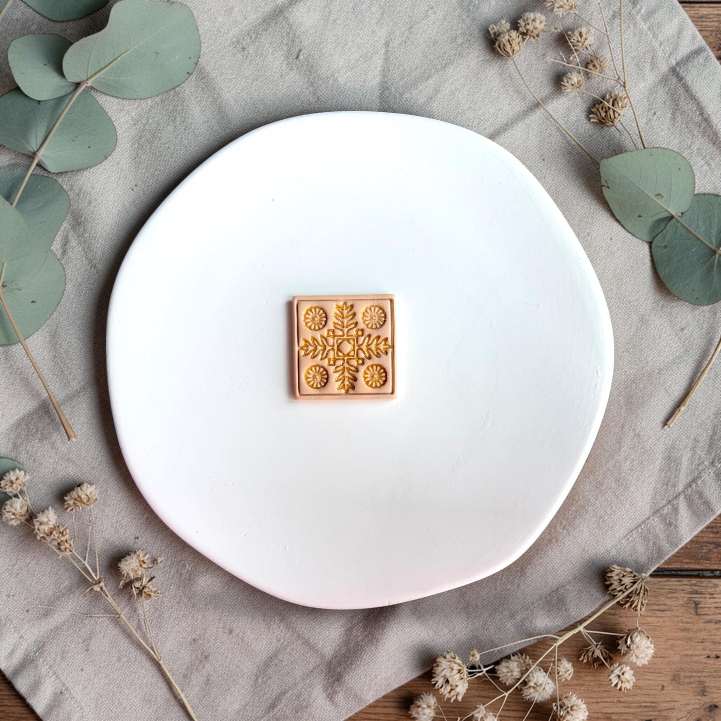 Finished clay piece with gold-highlighted Nordic floral tile design centered on a white plate.