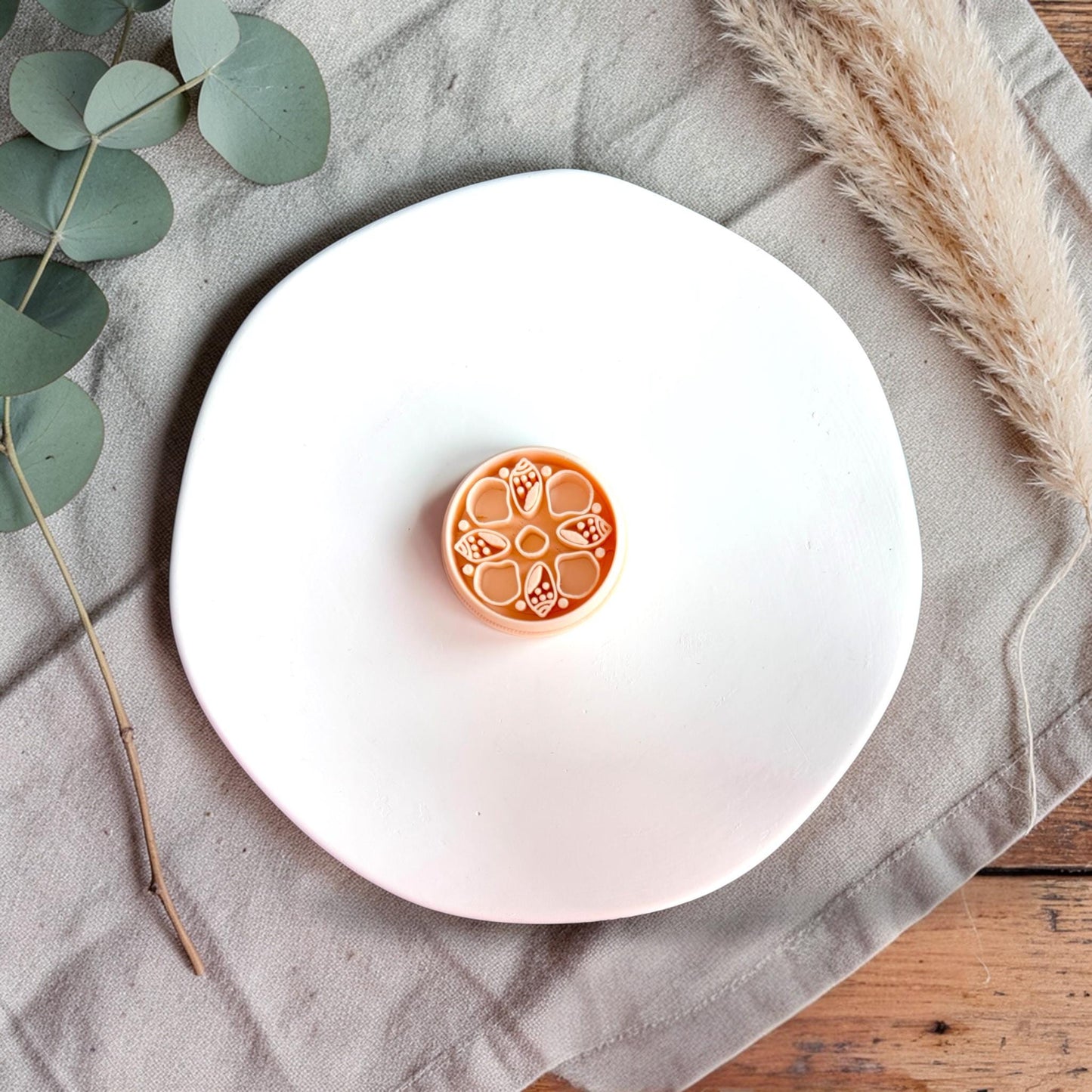 Single terracotta-colored clay cutter with raised sea shell floral pattern displayed on a white plate with neutral styling.