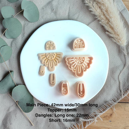 Cutter set shown with finished clay pieces including arch top, sunburst fan shape, and two dangling connector pieces with size details.