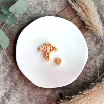 Manta ray shaped clay cutter with matching teardrop topper displayed on a white plate with soft neutral styling.