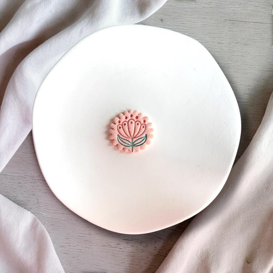 Finished clay flower piece showing detailed folk art design on white background