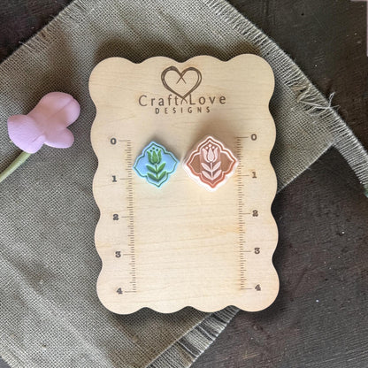 Two finished clay tulip charms in blue and peach on Craft Love Designs ruler board