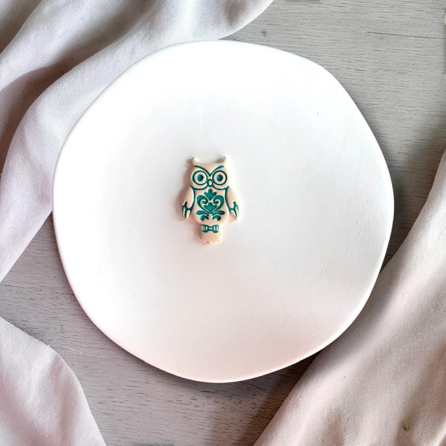 Finished owl clay piece showing detailed ornamental design on white background