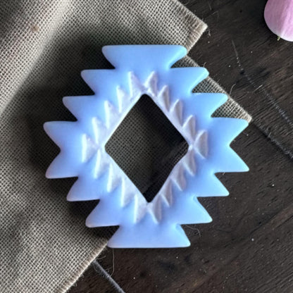 Finished blue clay aztec pattern charm on linen fabric