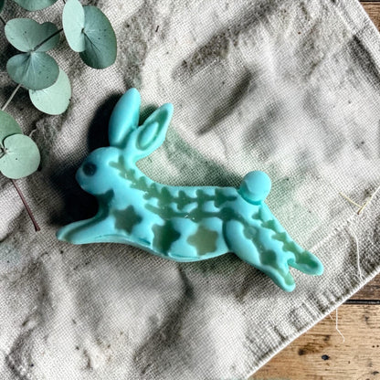 turquoise clay folk rabbit charm with embossed decorative pattern on linen fabric