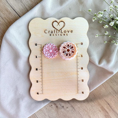 Daisy polymer clay cutter with scalloped edge on wooden sizing board