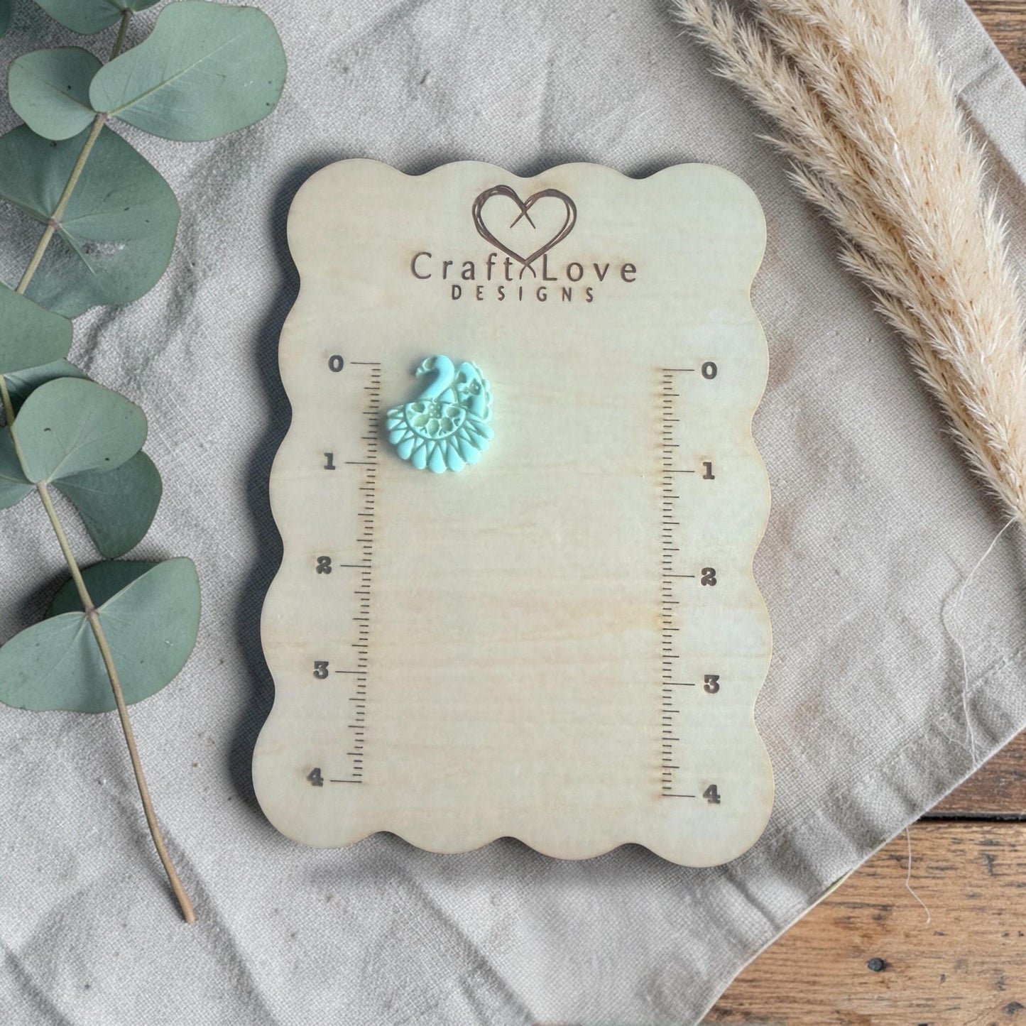 finished turquoise clay peacock charm shown on Craft Love Designs ruler board