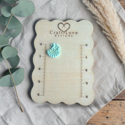finished turquoise clay peacock charm shown on Craft Love Designs ruler board