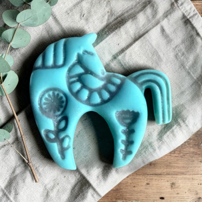 turquoise clay folk horse charm with embossed Scandinavian floral pattern on linen