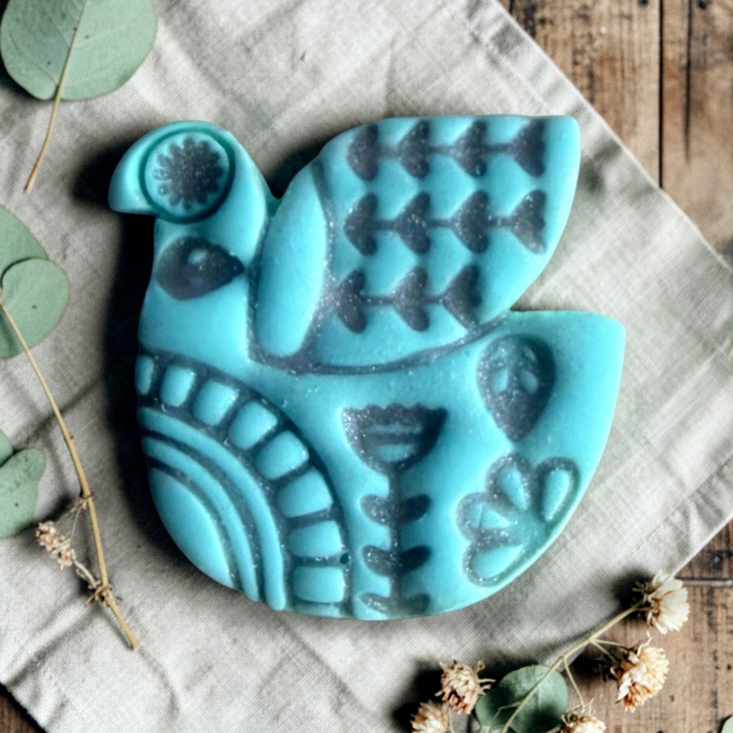 turquoise clay folk bird charm with embossed Scandinavian style pattern on linen