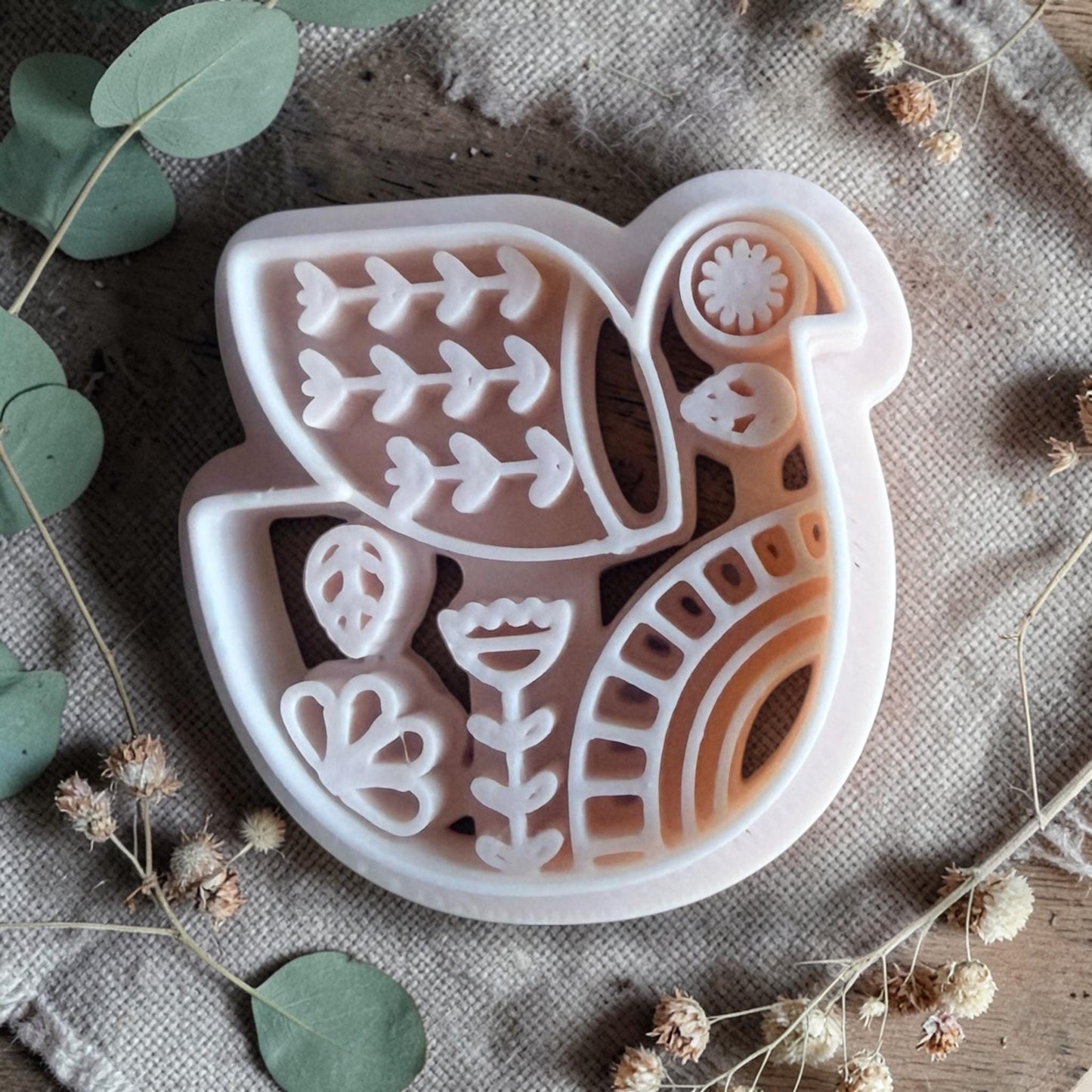 white polymer clay bird cutter with folk art pattern on fabric background
