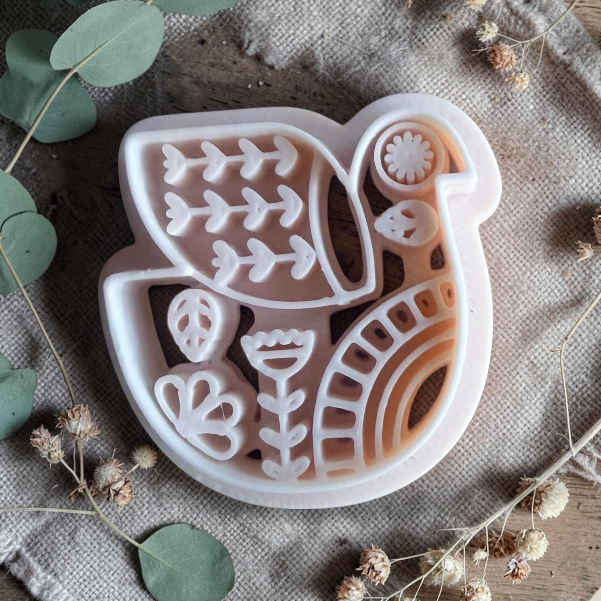 white polymer clay bird cutter with folk art pattern on fabric background