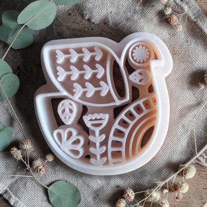 white polymer clay bird cutter with folk art pattern on fabric background