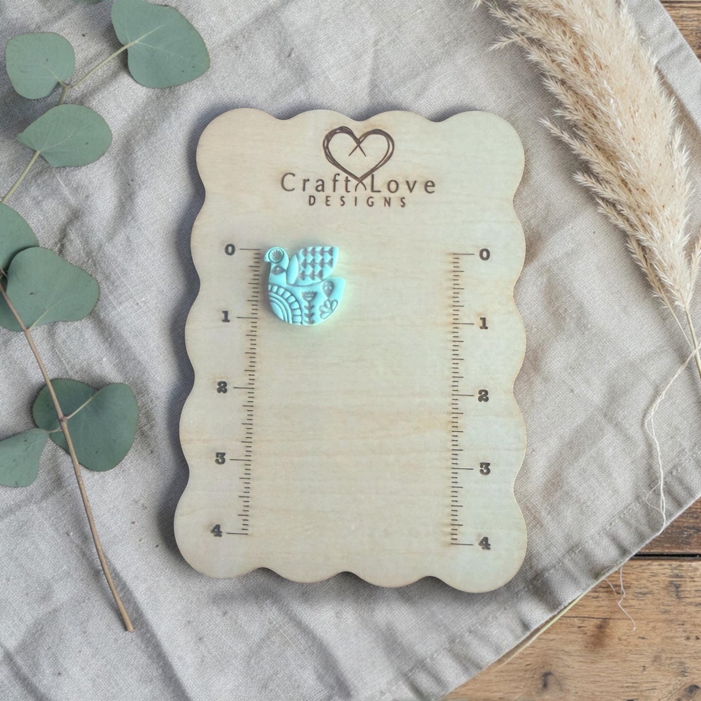 finished turquoise clay bird charm shown on Craft Love Designs ruler board