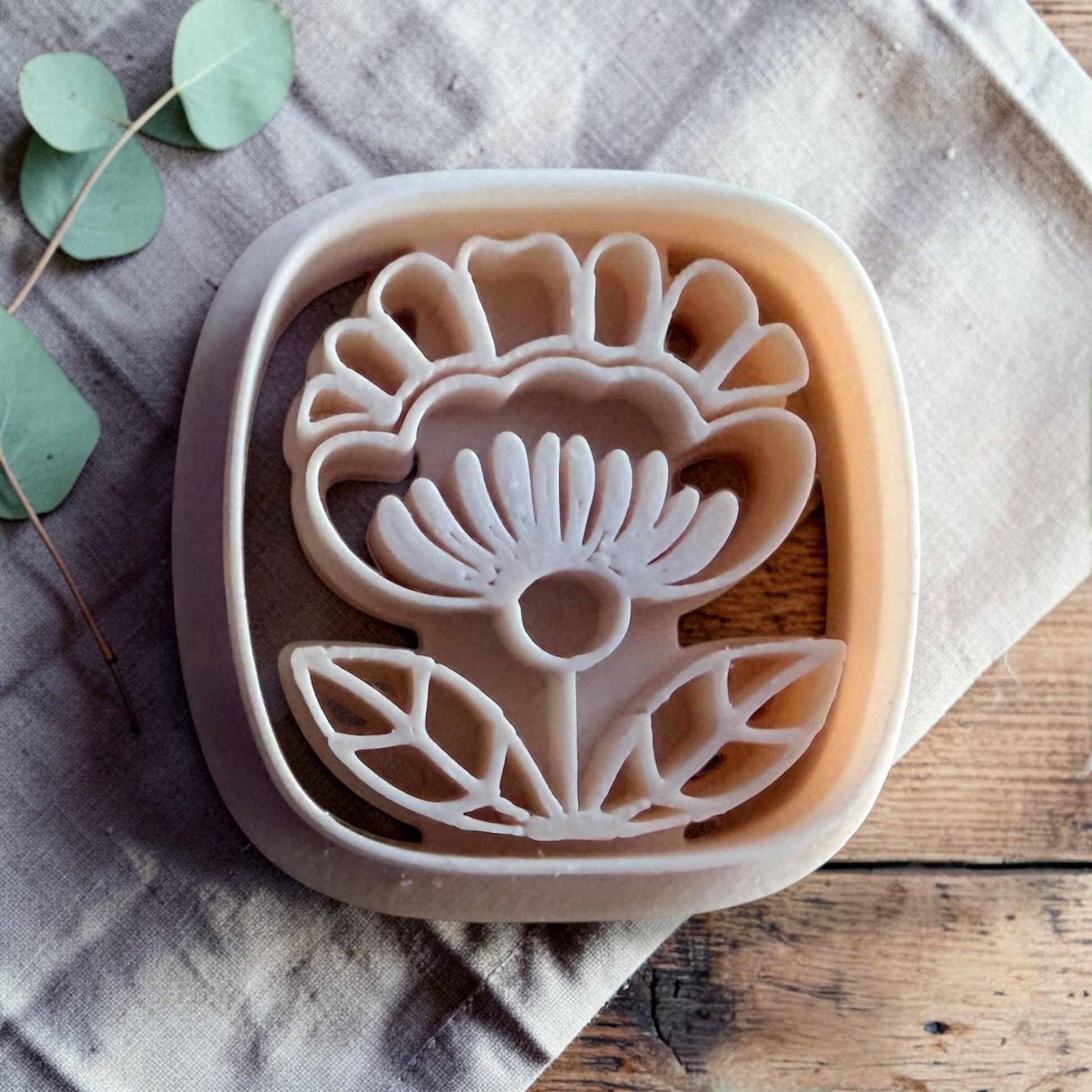 white polymer clay Scandinavian folk flower cutter on linen and wooden background