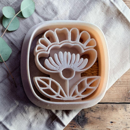 white polymer clay Scandinavian folk flower cutter on linen and wooden background