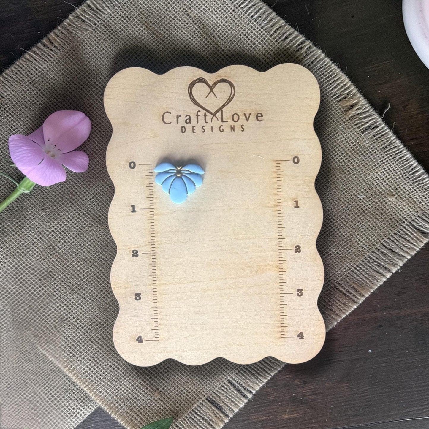 finished blue flower clay charm displayed on ruler board