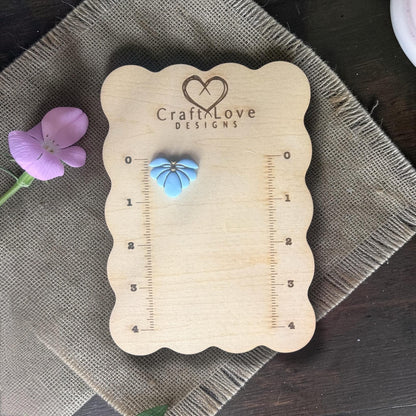 finished blue flower clay charm displayed on ruler board
