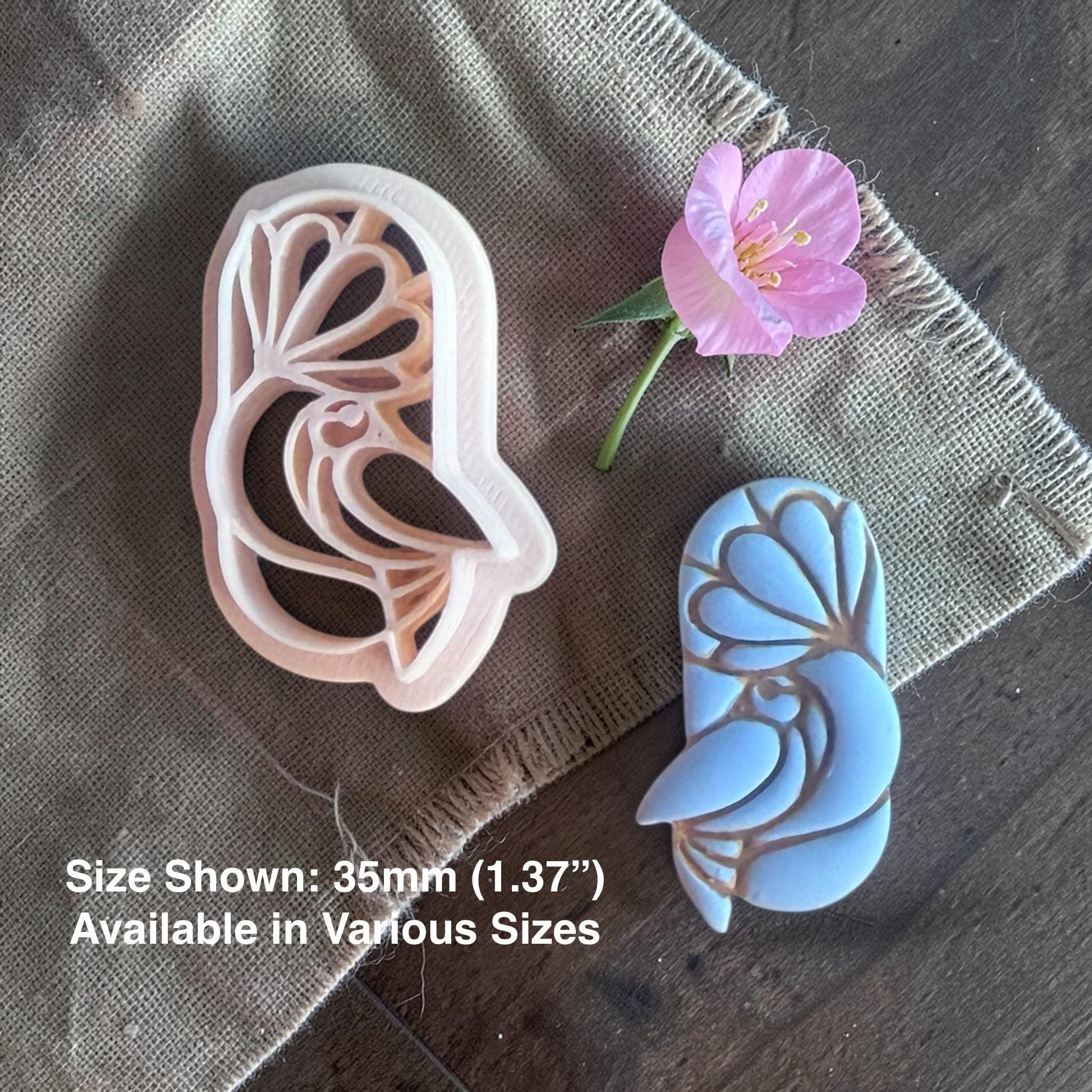 Bird under flower clay cutter next to finished clay piece.