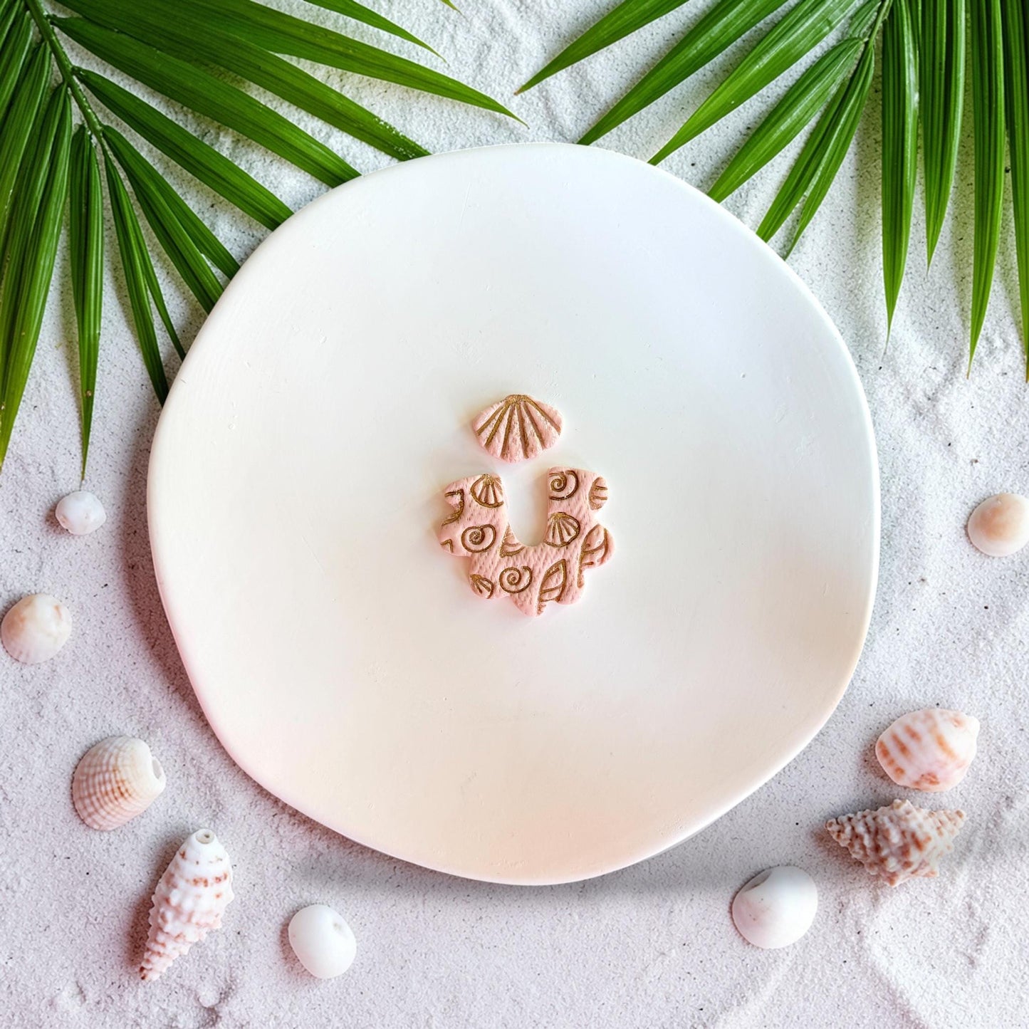 Close up of beach themed polymer clay cutter with shell texture and arch dangle shape