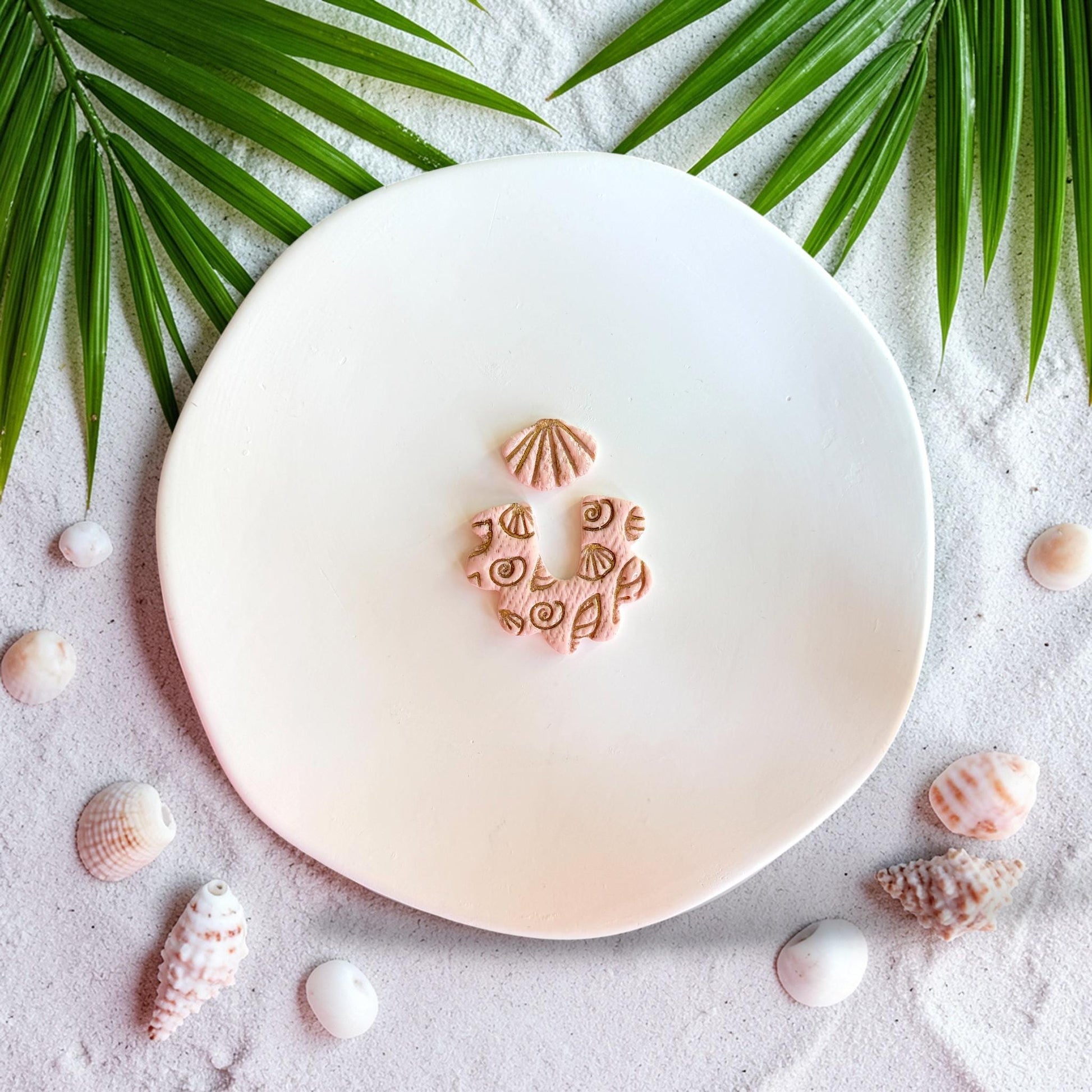 Close up of beach themed polymer clay cutter with shell texture and arch dangle shape
