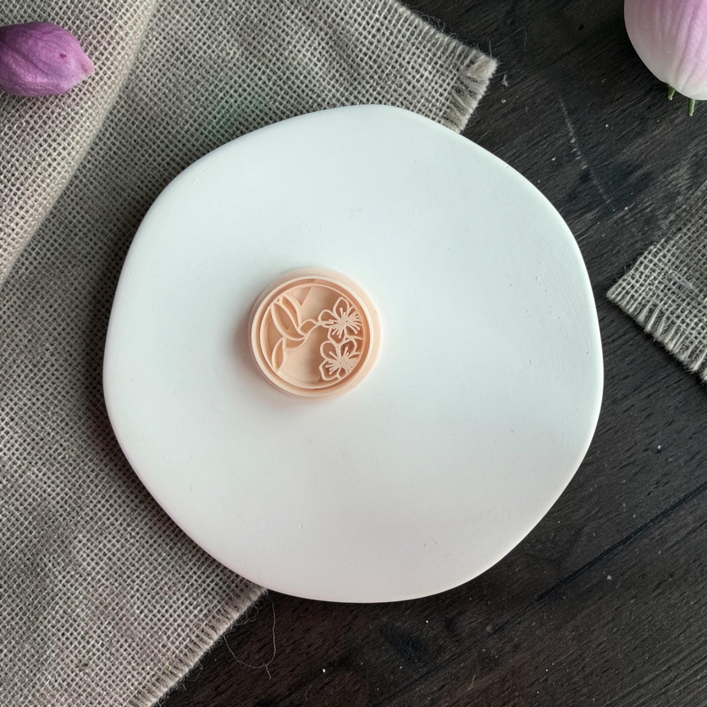 Close-up of the round polymer clay cutter showing hummingbird and floral detailing inside the circle shape.