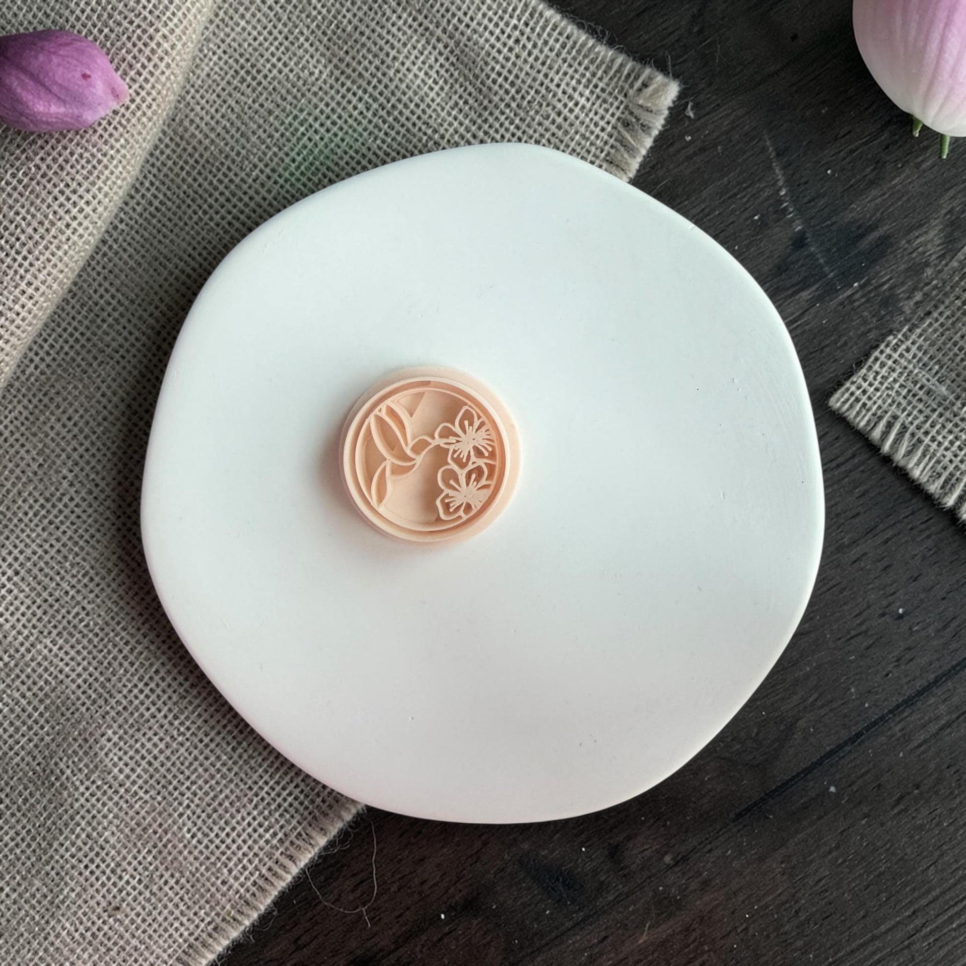 Close-up of the round polymer clay cutter showing hummingbird and floral detailing inside the circle shape.