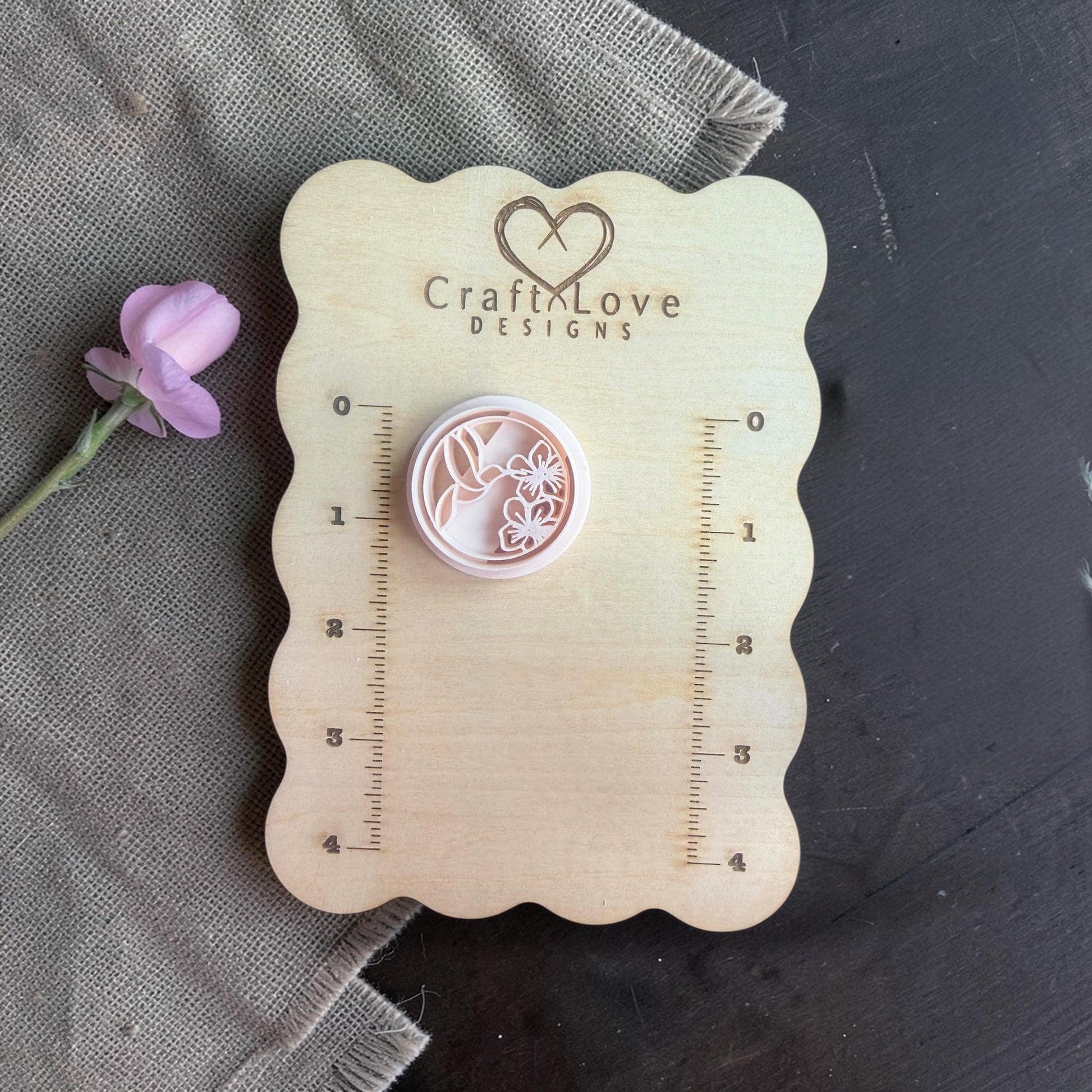 Close-up of the round polymer clay cutter showing hummingbird and floral detailing inside the circle shape.