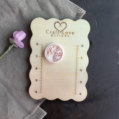 Close-up of the round polymer clay cutter showing hummingbird and floral detailing inside the circle shape.