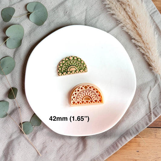 Two arch-shaped clay pieces side by side, one raw and one finished, showing the detailed pattern created by the cutter.