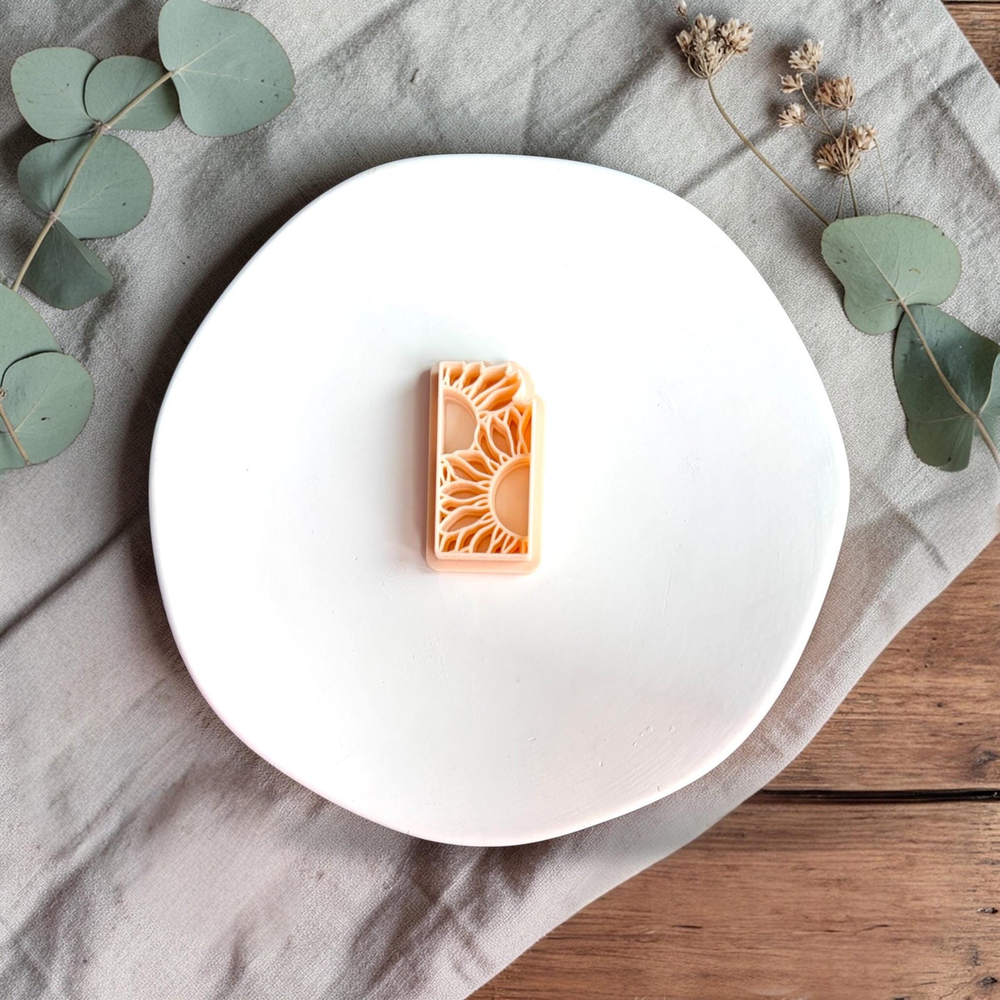 Close-up of rectangular polymer clay cutter with layered sunflower petal design on a white background.