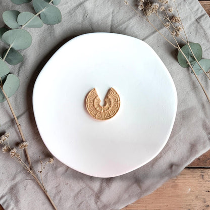 Finished clay piece in a U-shaped arch design with detailed pattern centered on a white plate.