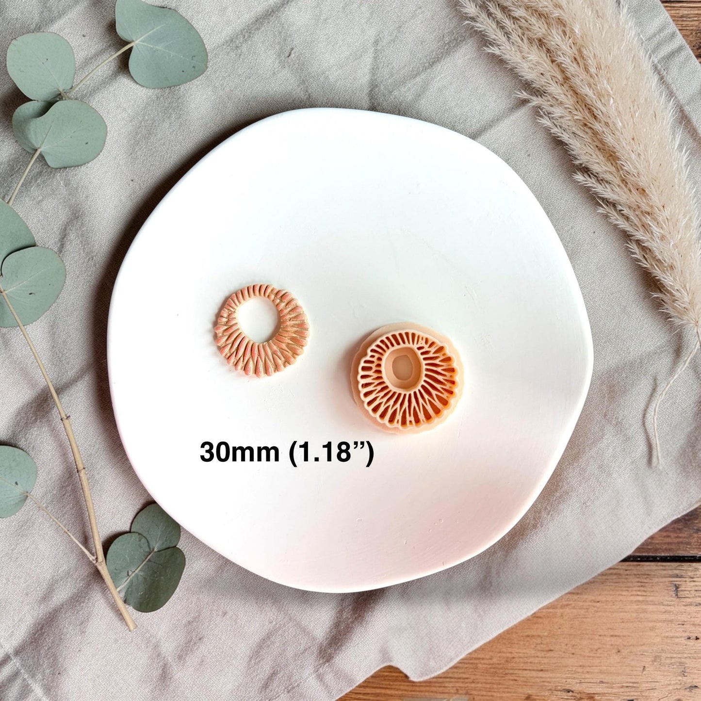 Polymer clay cutter and finished clay ring side by side with text showing size 30mm on a white plate.