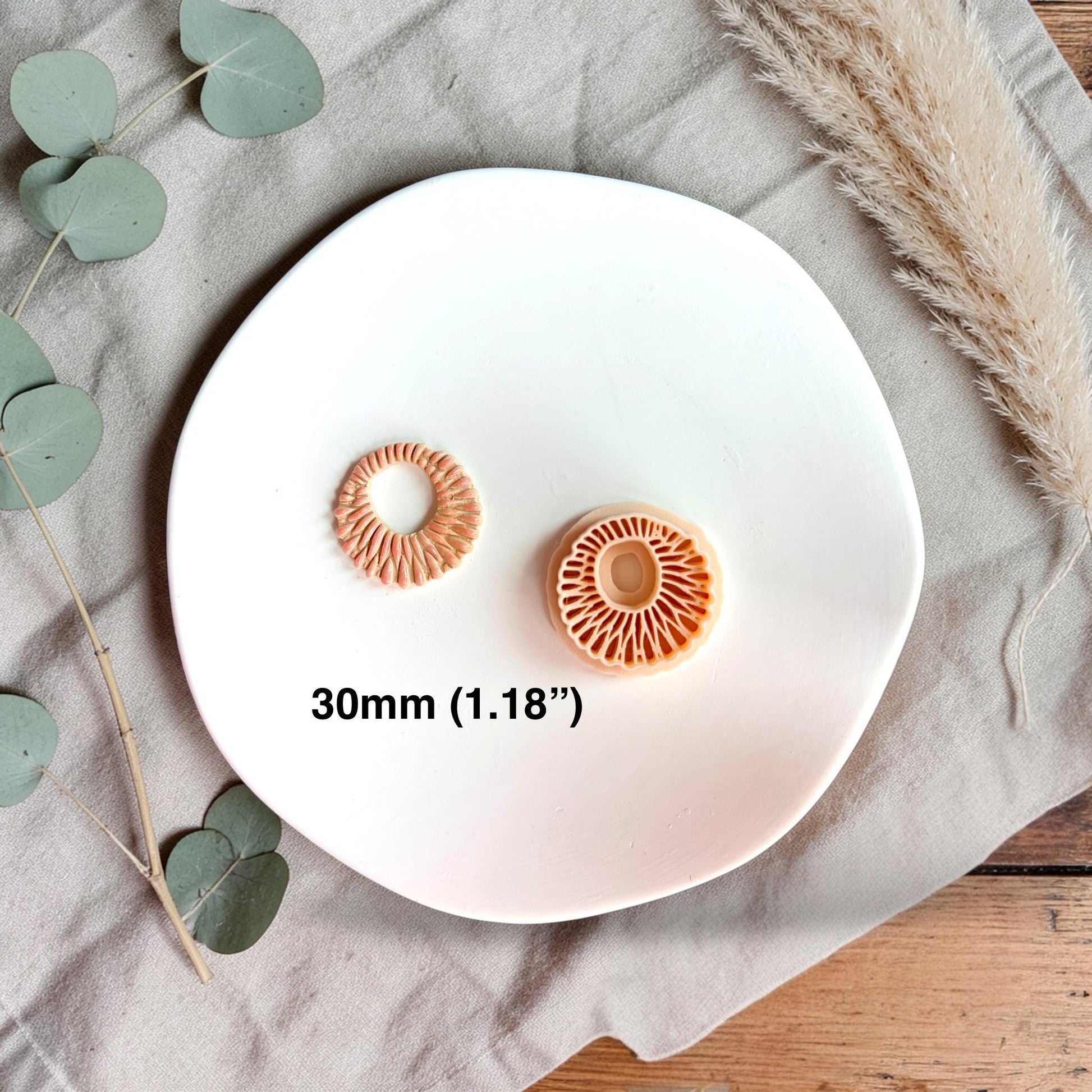 Polymer clay cutter and finished clay ring side by side with text showing size 30mm on a white plate.