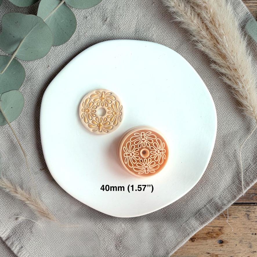 Finished clay piece with circular boho floral pattern and center hole displayed next to the cutter with size text 40mm.