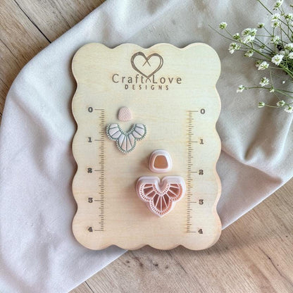 Polymer clay cutter set with boho fan wing shape and matching top stud displayed on a wooden measuring board with ruler markings.